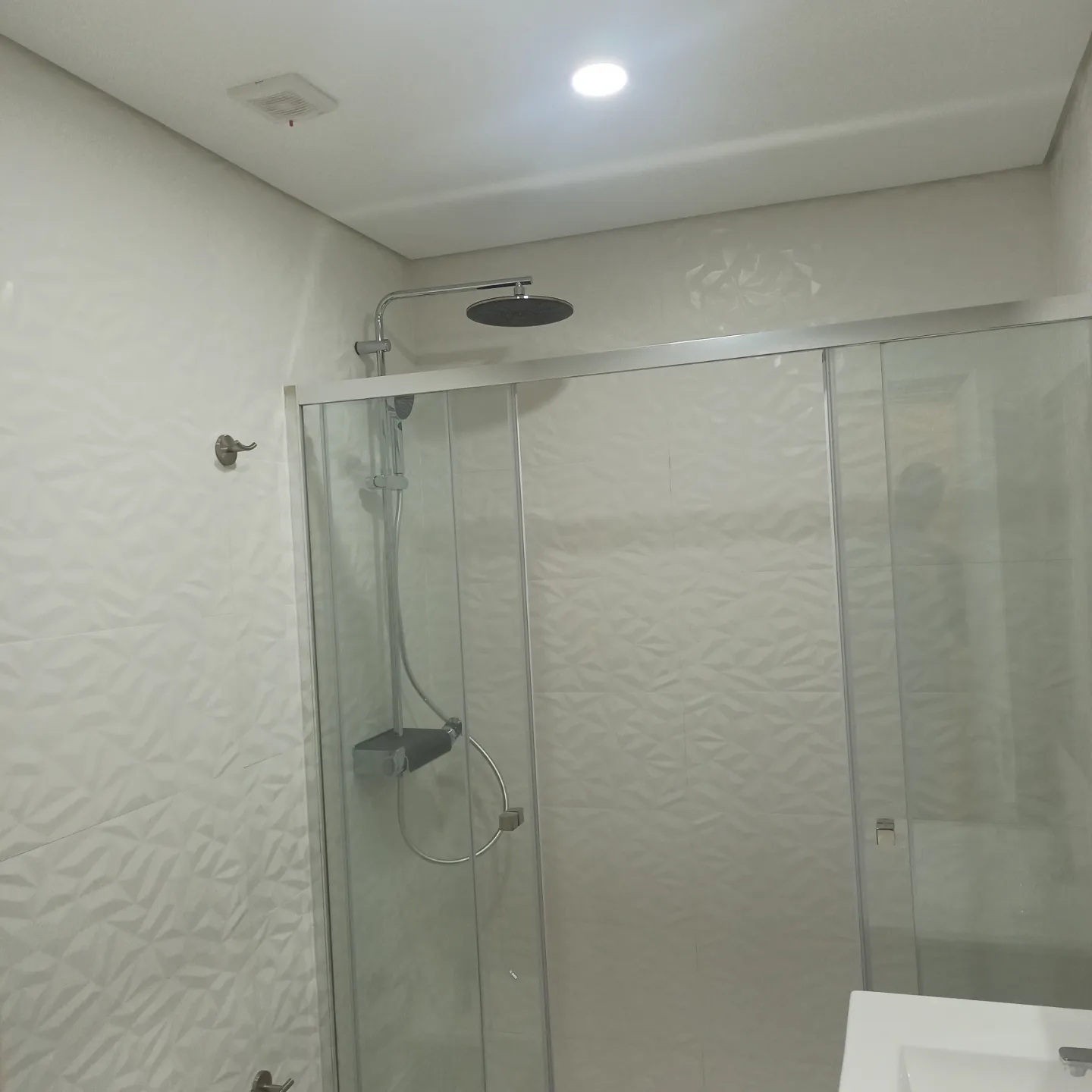 Zona de duche concluída numa casa de banho remodelada, com revestimentos claros