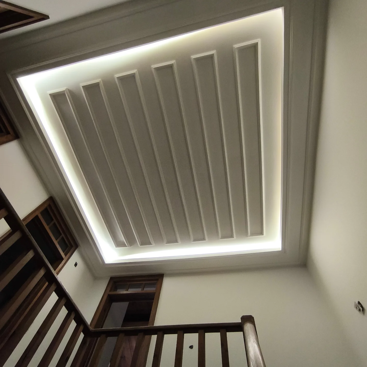 Detalhe geométrico de teto com molduras e iluminação concluídos após preparação e pintura
